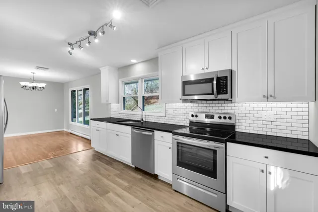 a kitchen with stainless steel appliances kitchen island granite countertop a stove top oven a sink dishwasher and a microwave oven on the blue kitchen countertops