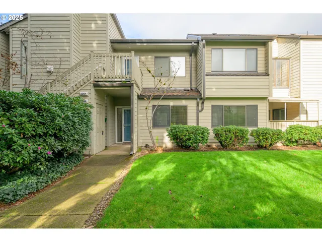 a view of a brick house with a yard potted plants and a table