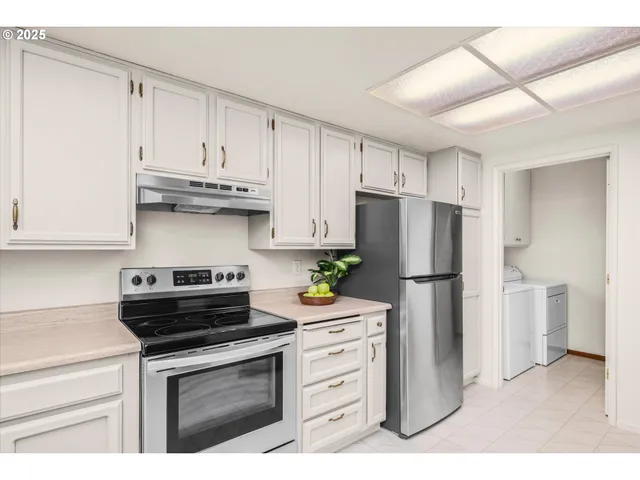 a kitchen with white cabinets and window