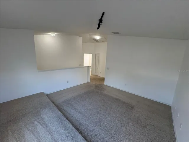 an empty room with a chandelier fan and windows