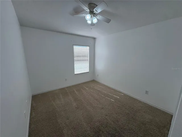 an empty room with a window and a ceiling fan