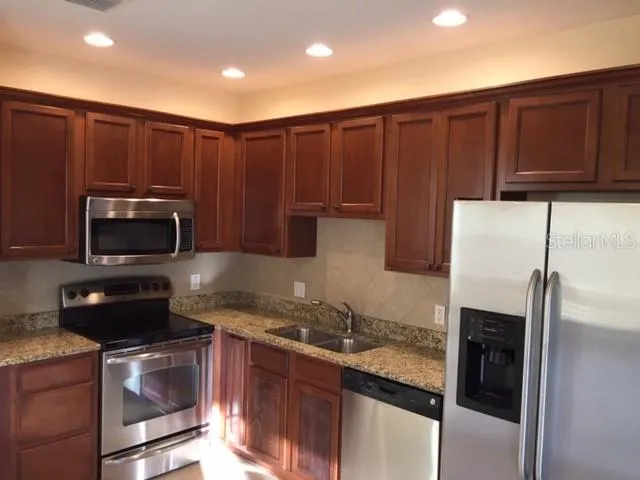 a kitchen with granite countertop stainless steel appliances and wooden cabinets