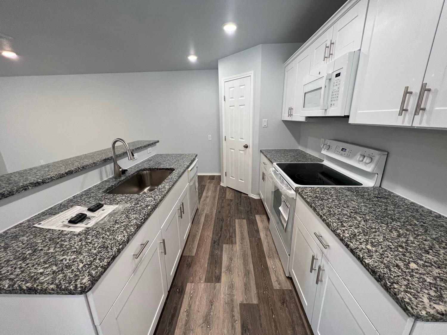 5611 Jarvis Street, Unit B Lubbock, TX 79416 - Photo 19 of 20 a kitchen with granite countertop a sink stove and cabinets