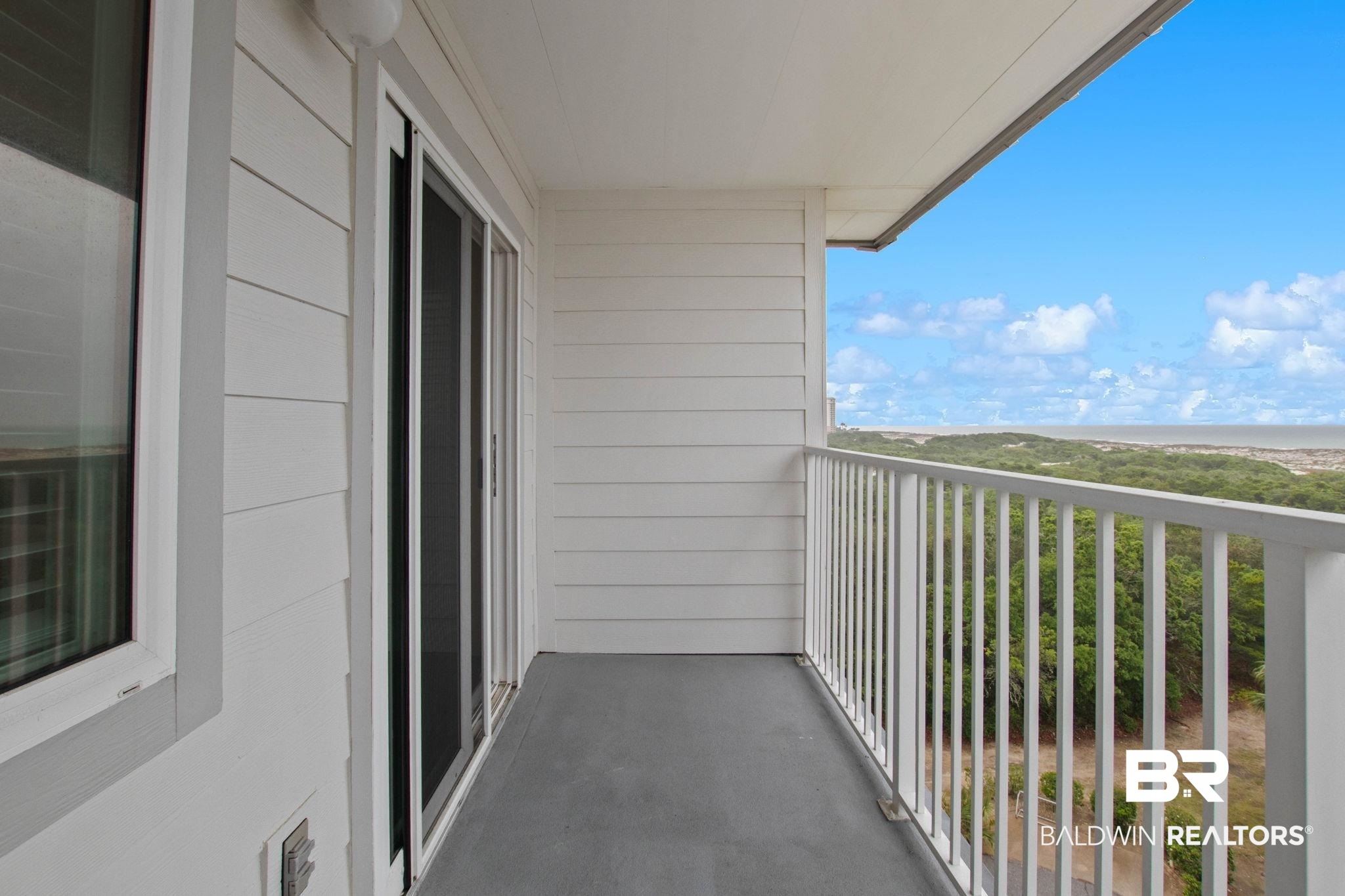 400 Plantation Road, Unit 4501 Gulf Shores, AL 36542 - Photo 9 of 30 Balcony with white panel siding, a dark gray floor, and a white metal railing overlooking distant water and greenery