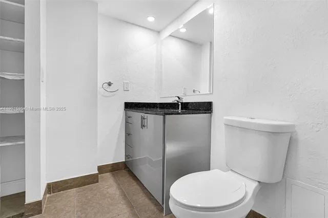 a bathroom with a granite countertop toilet and a sink