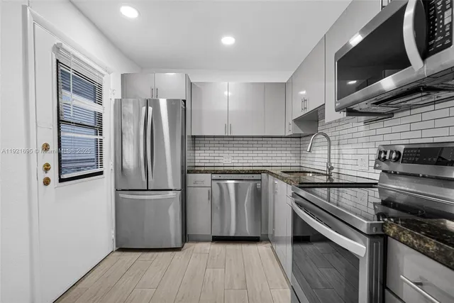 a kitchen with a refrigerator stove and wooden floor