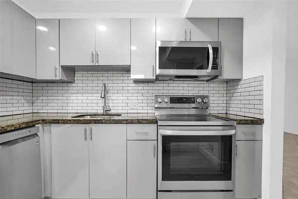 a kitchen with stainless steel appliances granite countertop a stove top oven microwave and cabinets