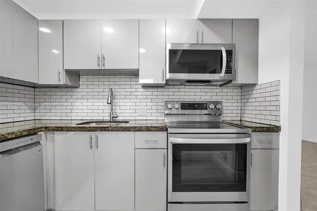 a kitchen with stainless steel appliances granite countertop a stove top oven microwave and cabinets