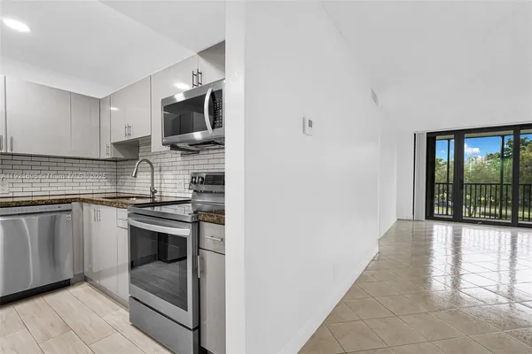 a kitchen with stainless steel appliances granite countertop a stove a sink and a microwave