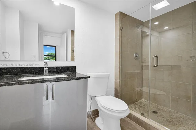 a bathroom with a granite countertop sink a toilet and shower