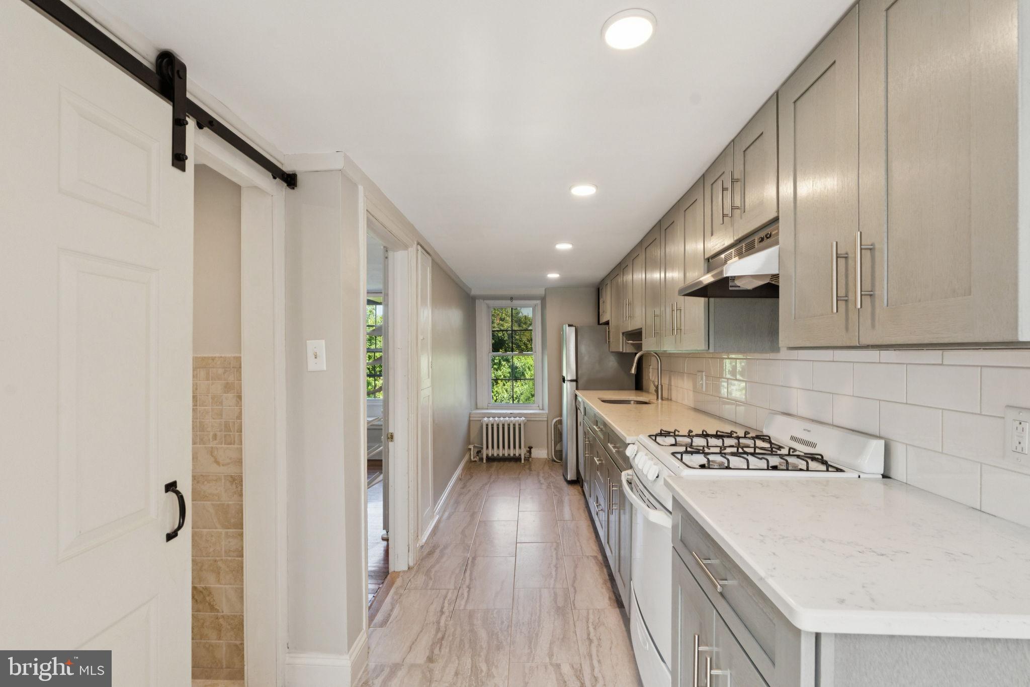 3715 Calumet Street, Unit 3 Philadelphia, PA 19129 - Photo 7 of 19 a kitchen with stainless steel appliances granite countertop a sink stove and refrigerator