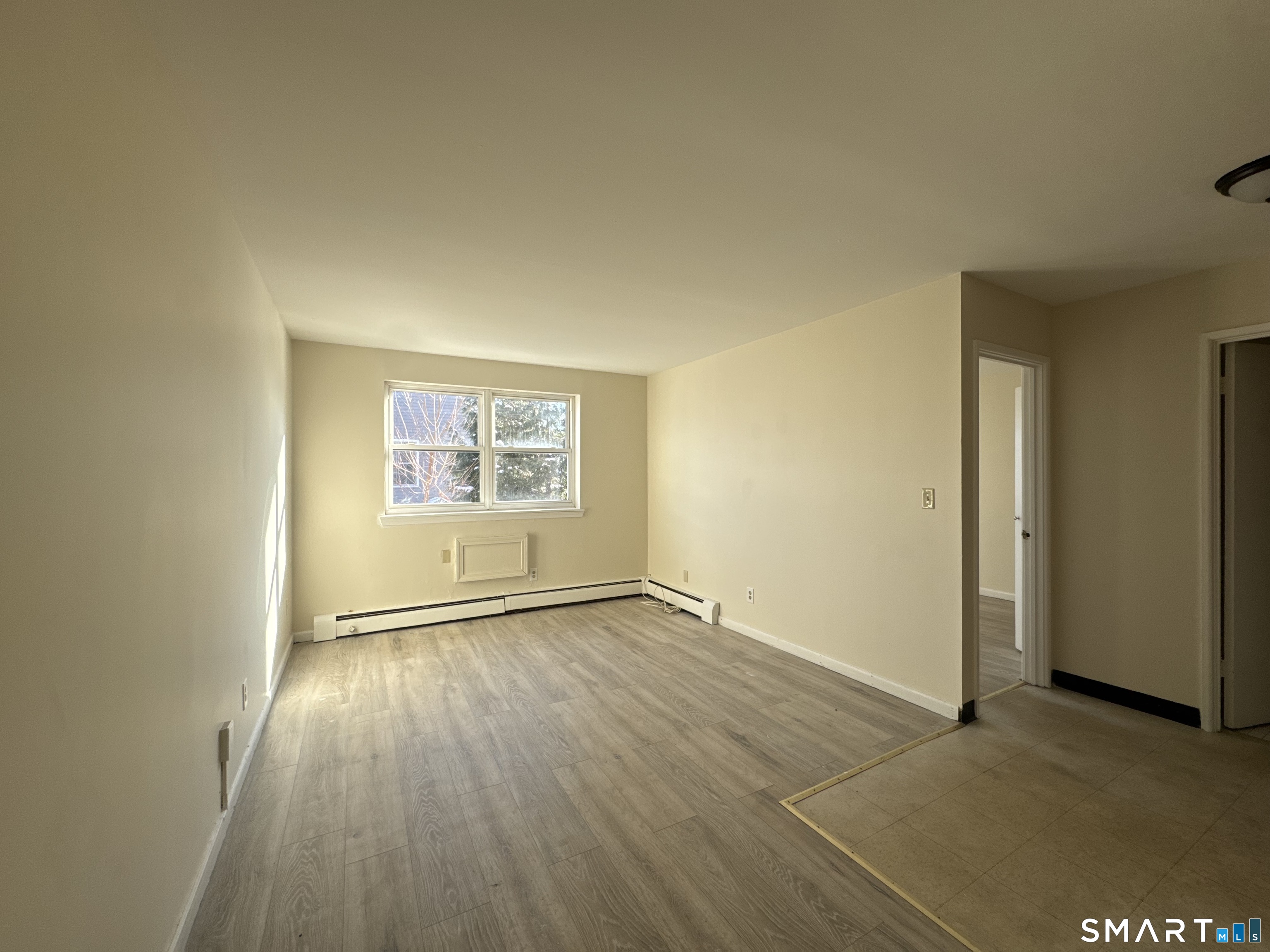 145 Cowles Street, Unit B3 Bridgeport, CT 06607 - Photo 2 of 8 an empty room with wooden floor and windows