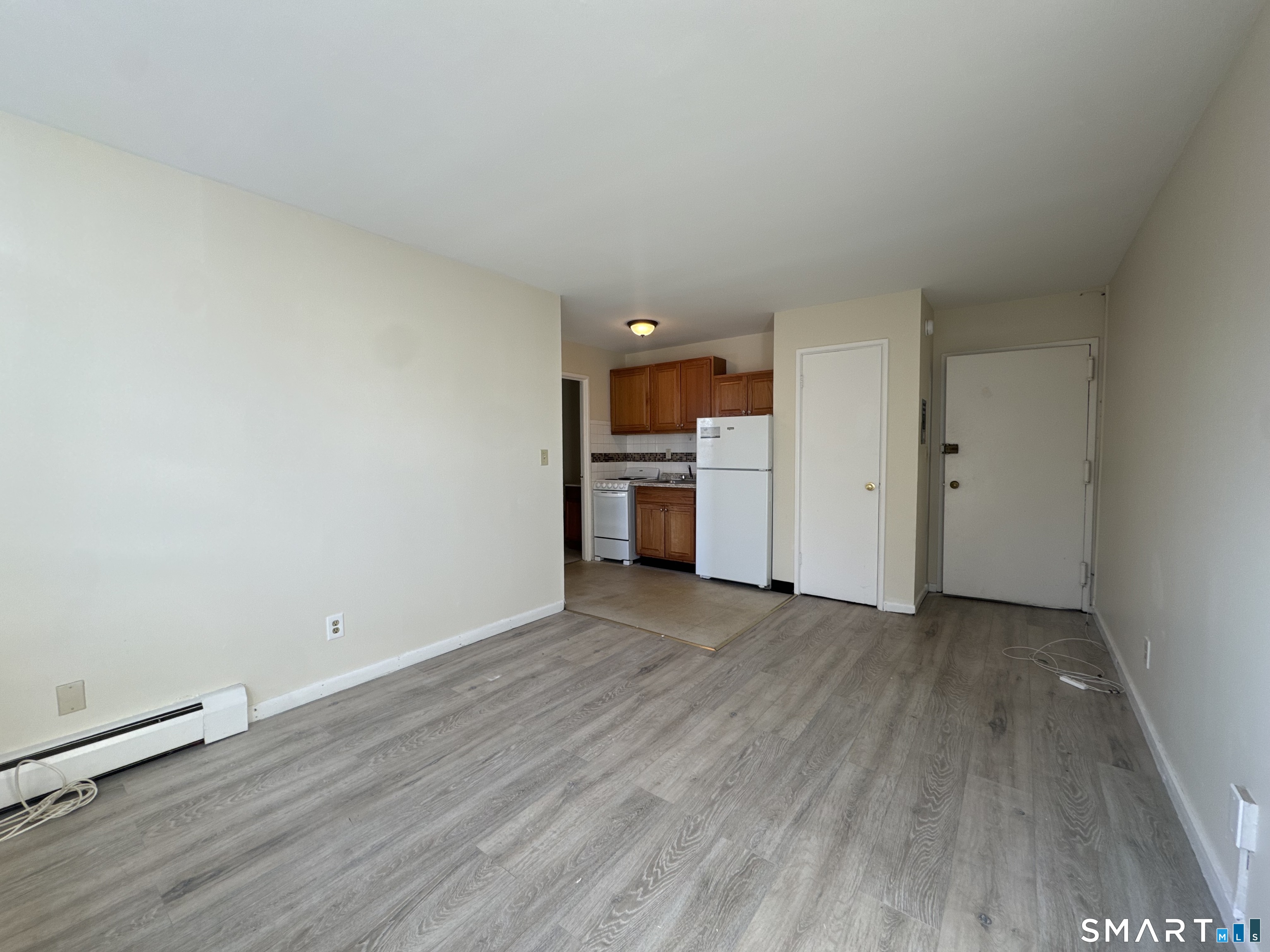 145 Cowles Street, Unit B3 Bridgeport, CT 06607 - Photo 3 of 8 a view of empty room with wooden floor and kitchen