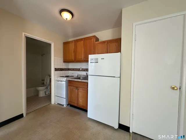 a kitchen with sink a refrigerator and white cabinets