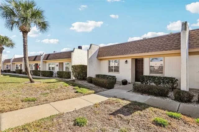 a front view of a house with garden space and palm tree