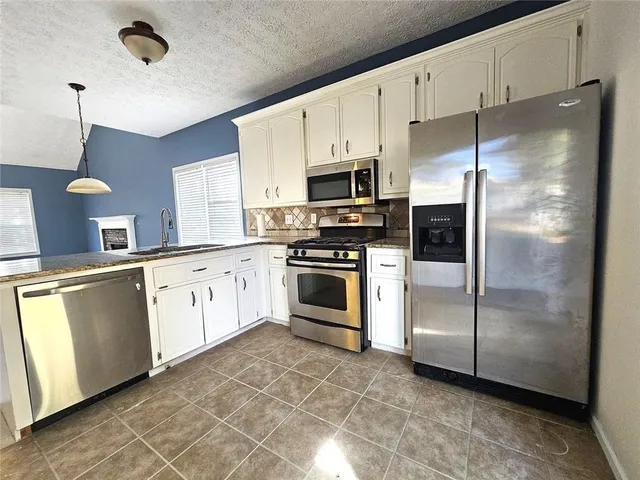 a kitchen with stainless steel appliances a refrigerator sink and microwave