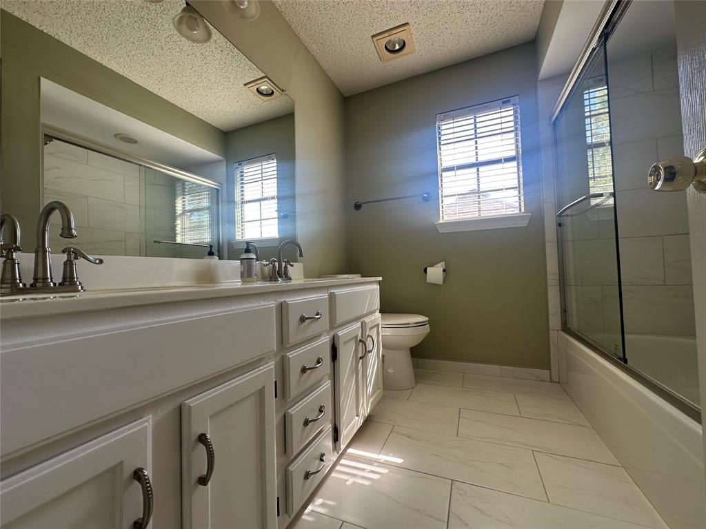 4342 Timberglen Road Dallas, TX 75287 - Photo 21 of 27 Full bathroom featuring double vanity, light marble finish flooring, enclosed tub / shower combo, and a textured ceiling