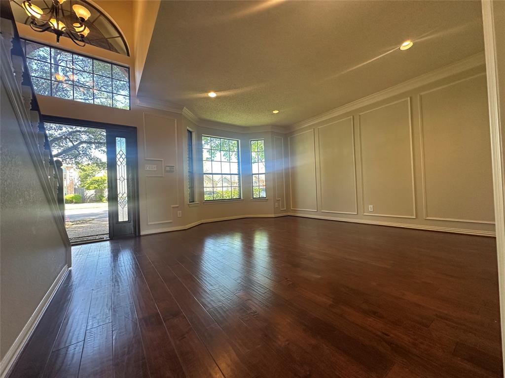 4342 Timberglen Road Dallas, TX 75287 - Photo 7 of 27 Entryway with a decorative wall, dark wood-style flooring, a chandelier, and ornamental molding