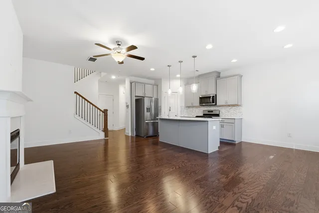 a large kitchen with granite countertop a stove a sink a refrigerator and white cabinets with wooden floor