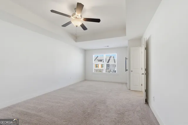an empty room with windows and fan
