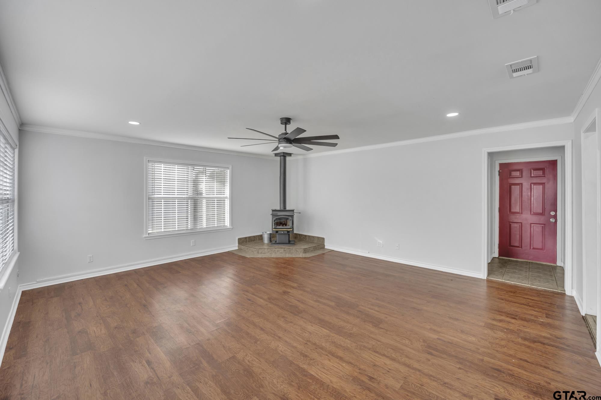 3743 Smelley Road Longview, TX 75605 - Photo 8 of 25 an empty room with wooden floor chandelier fan and windows