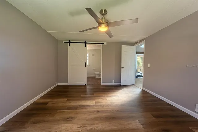 an empty room with wooden floor and a ceiling fan