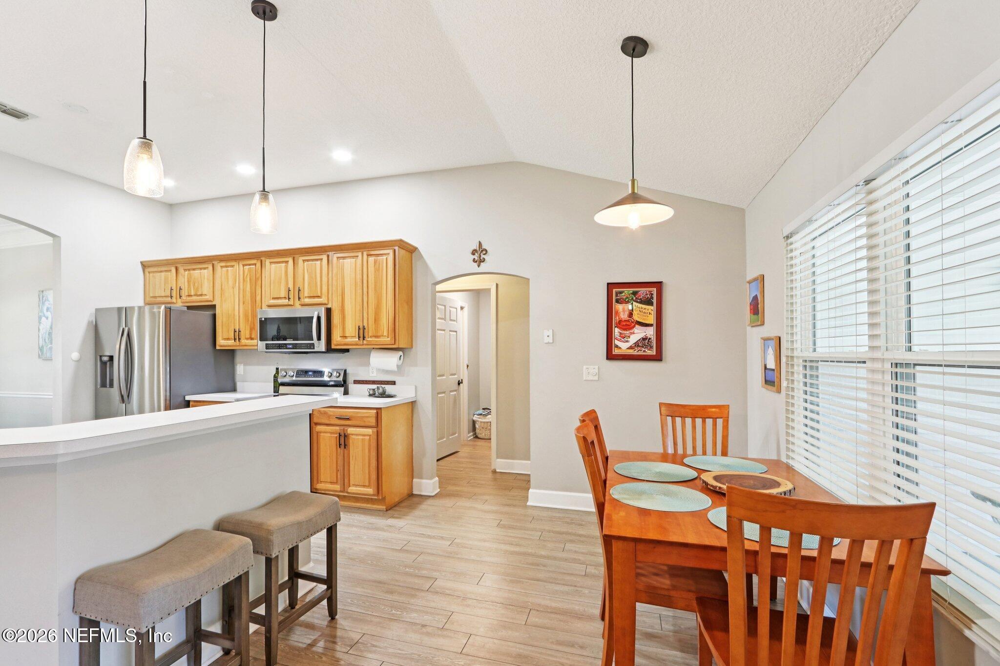 1405 Sinclair Lane Jacksonville, FL 32221 - Photo 15 of 37 a kitchen with stainless steel appliances granite countertop a stove top oven a refrigerator a dining table and chairs with wooden floor