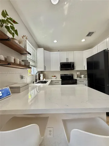 a kitchen with stainless steel appliances granite countertop a refrigerator and a stove top oven