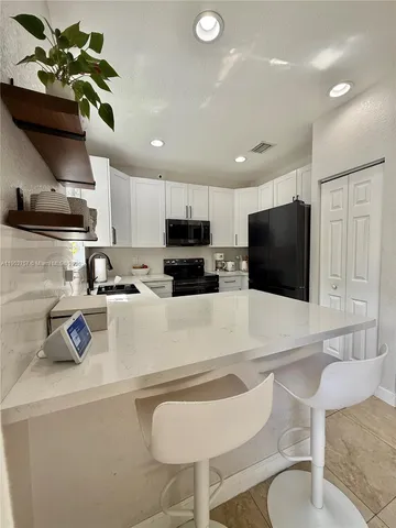 a kitchen with stainless steel appliances granite countertop a sink a stove a microwave a refrigerator and cabinets