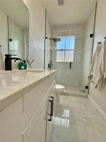 a bathroom with a sink a toilet and shower