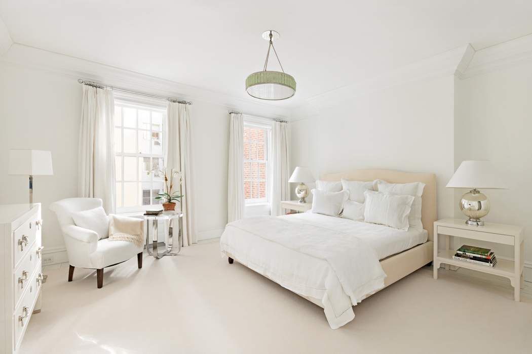 10 East 73rd Street Manhattan, NY 10021 - Photo 12 of 16 a spacious bedroom with a bed and a chandelier
