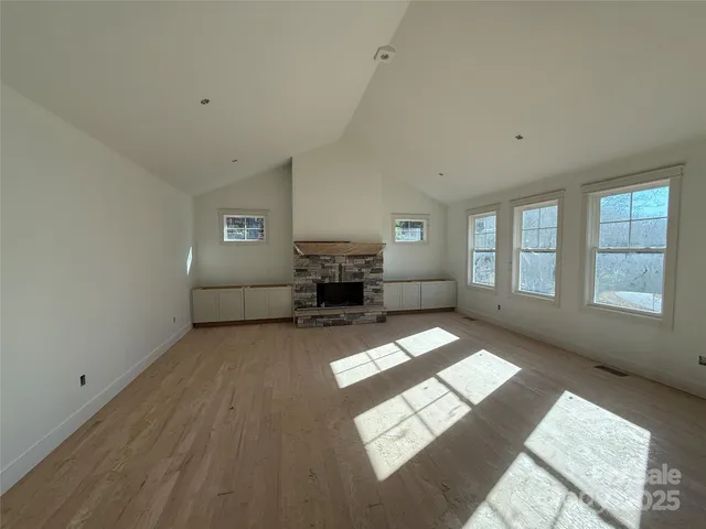 a view of an empty room with fireplace and a window