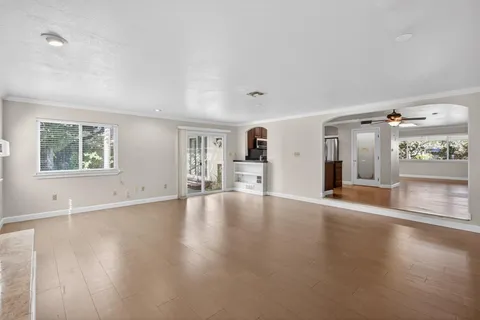 a view of an empty room with a window and wooden floor
