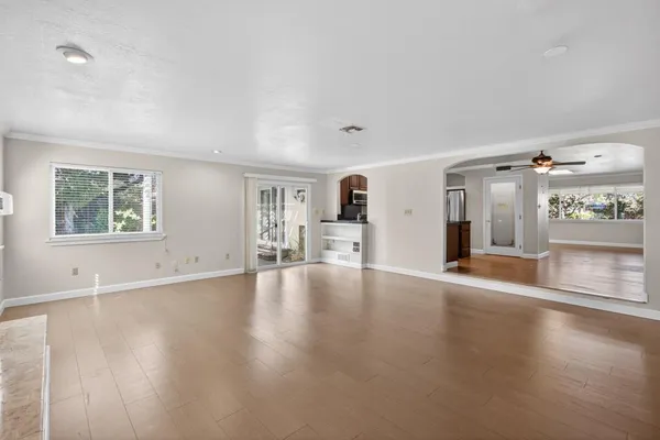 a view of an empty room with a window and wooden floor