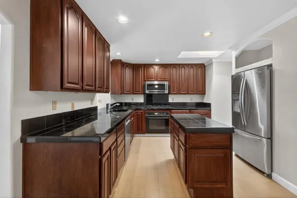 a kitchen with granite countertop wooden cabinets a refrigerator and a sink