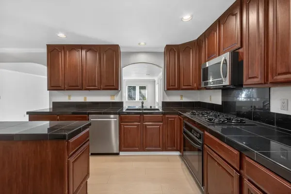 a kitchen with stainless steel appliances granite countertop wooden cabinets stove top oven and granite counter top