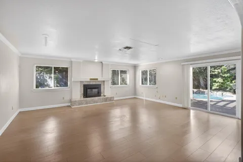 a view of empty room with wooden floor and fireplace