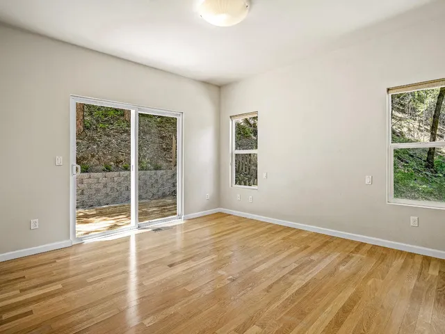 an empty room with wooden floor and windows