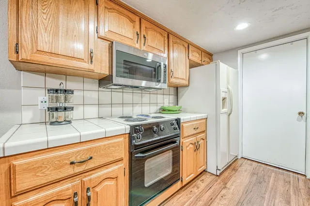 a kitchen with stainless steel appliances granite countertop a refrigerator and a stove top oven