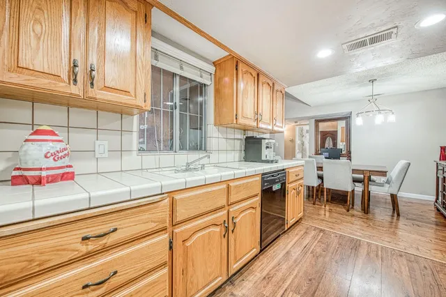 a kitchen with stainless steel appliances granite countertop a sink dishwasher and cabinets with wooden floor