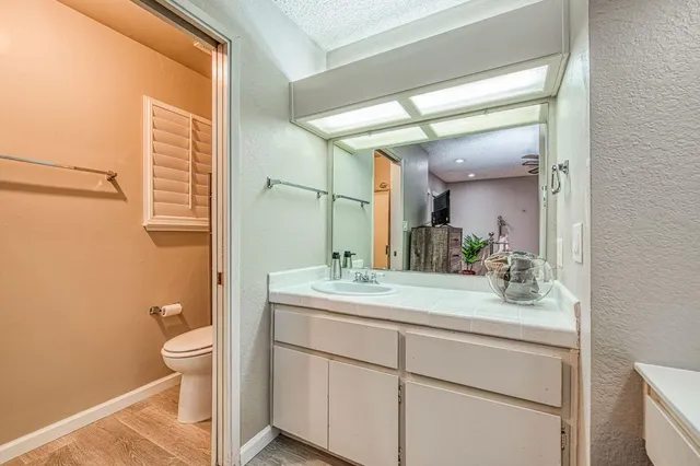 a bathroom with a granite countertop sink toilet a large mirror and a shower