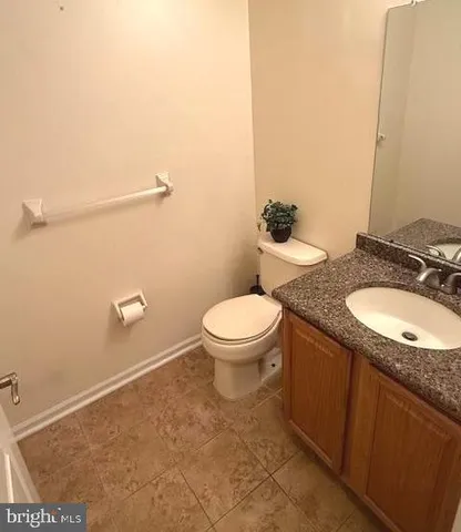 a bathroom with a granite countertop sink a toilet and a mirror