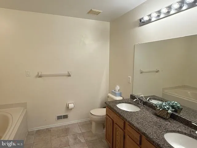 a bathroom with a granite countertop sink a toilet and a mirror
