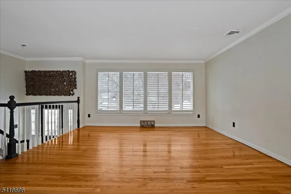 a view of empty room with wooden floor and windows
