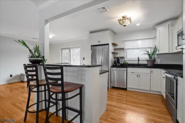 a kitchen with stainless steel appliances kitchen island granite countertop a dining table chairs and a refrigerator