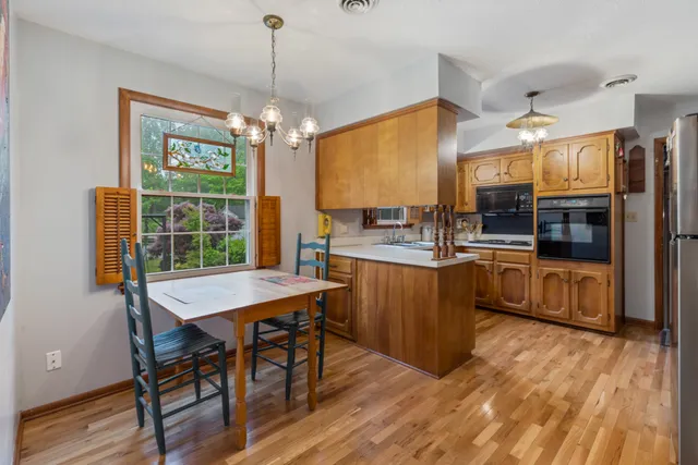 a kitchen with stainless steel appliances wooden floor dining table and chairs