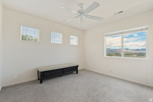 14883 Tooele Lane Draper, UT 84020 - Photo 28 of 49 Spacious room featuring a large picture window, three smaller windows, light gray carpet, and a white ceiling fan