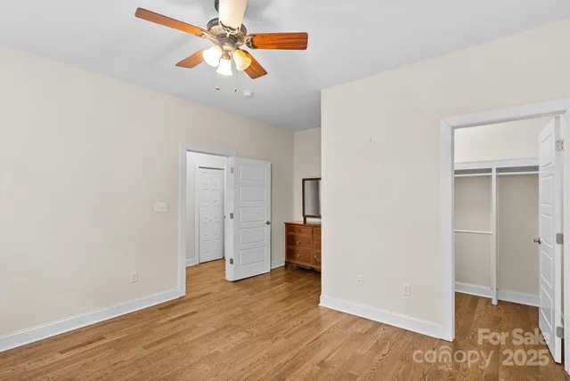an empty room with wooden floor chandelier fan and closet