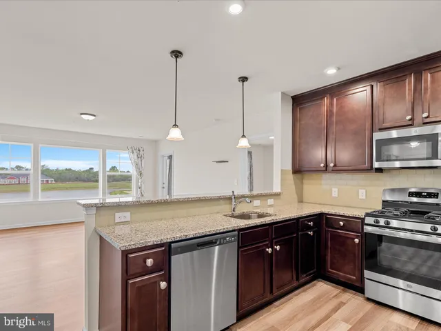 a kitchen with stainless steel appliances granite countertop a refrigerator a sink a stove a microwave and island