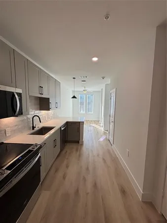 a large kitchen with a wooden floor and stainless steel appliances